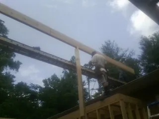 Carpenter setting a ridge beam over a new addition frame in Kent